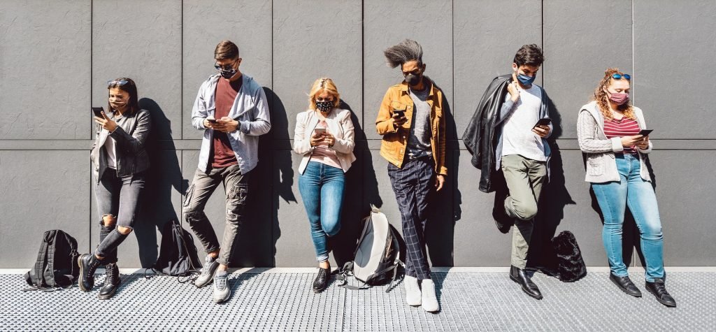 Multiracial people using mobile smart phone with face mask covered